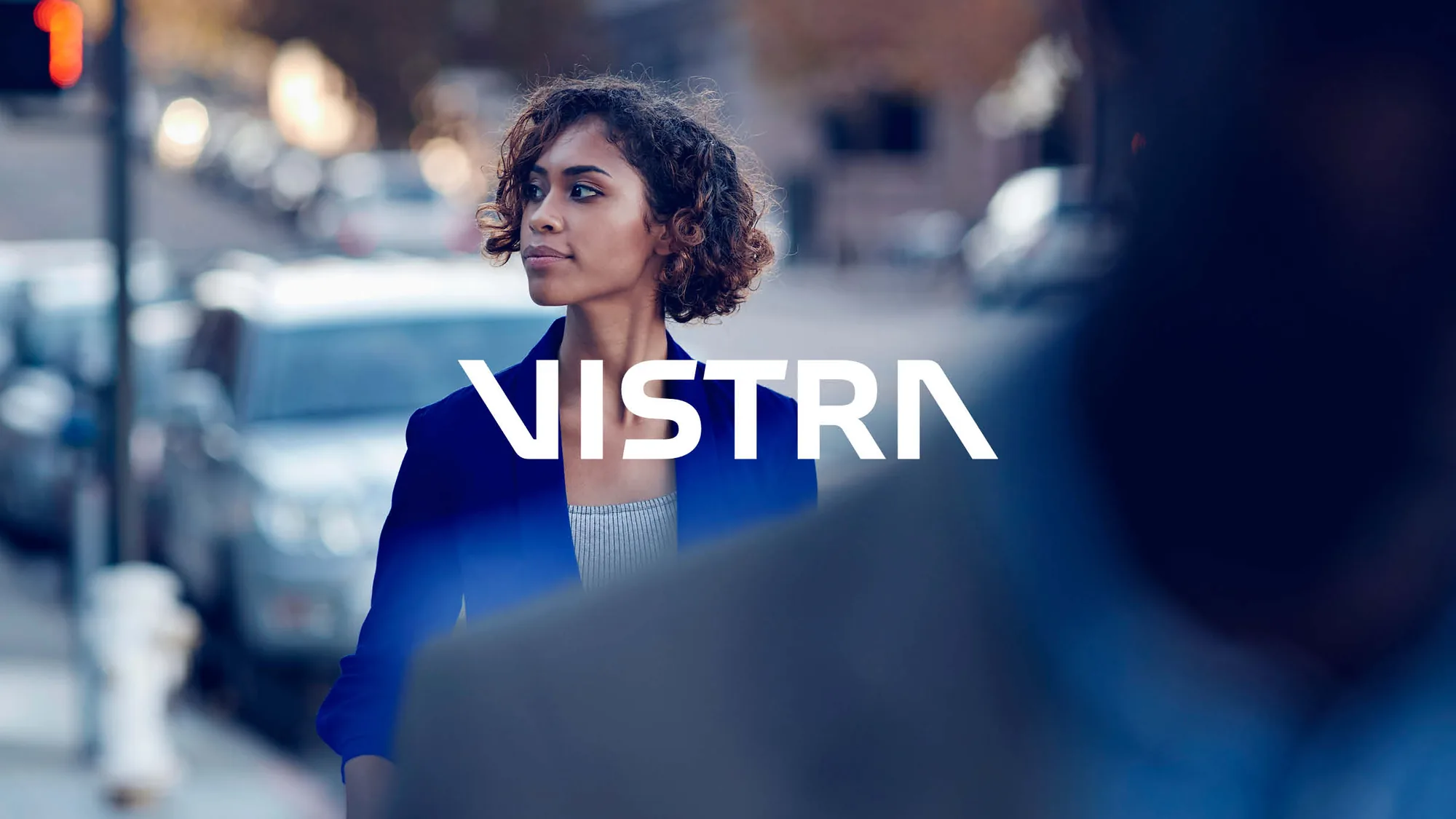 Vistra brand image: logo over a businesswoman on a city street